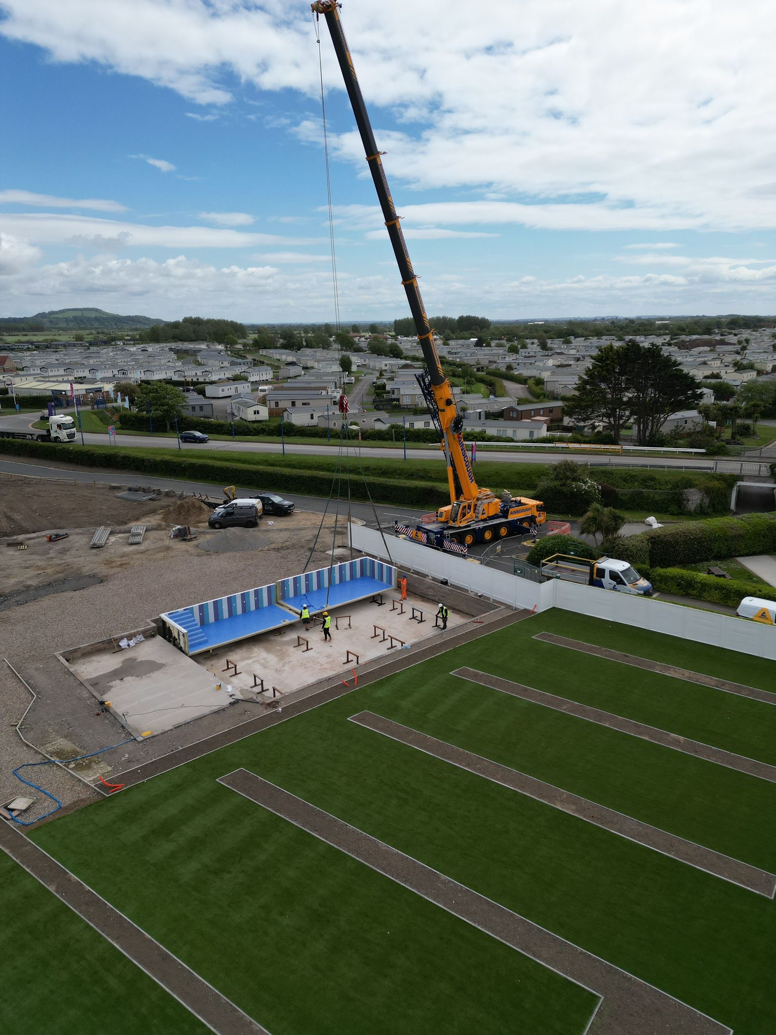 Crane lifting prefabricated pool sections into position on the prepared base