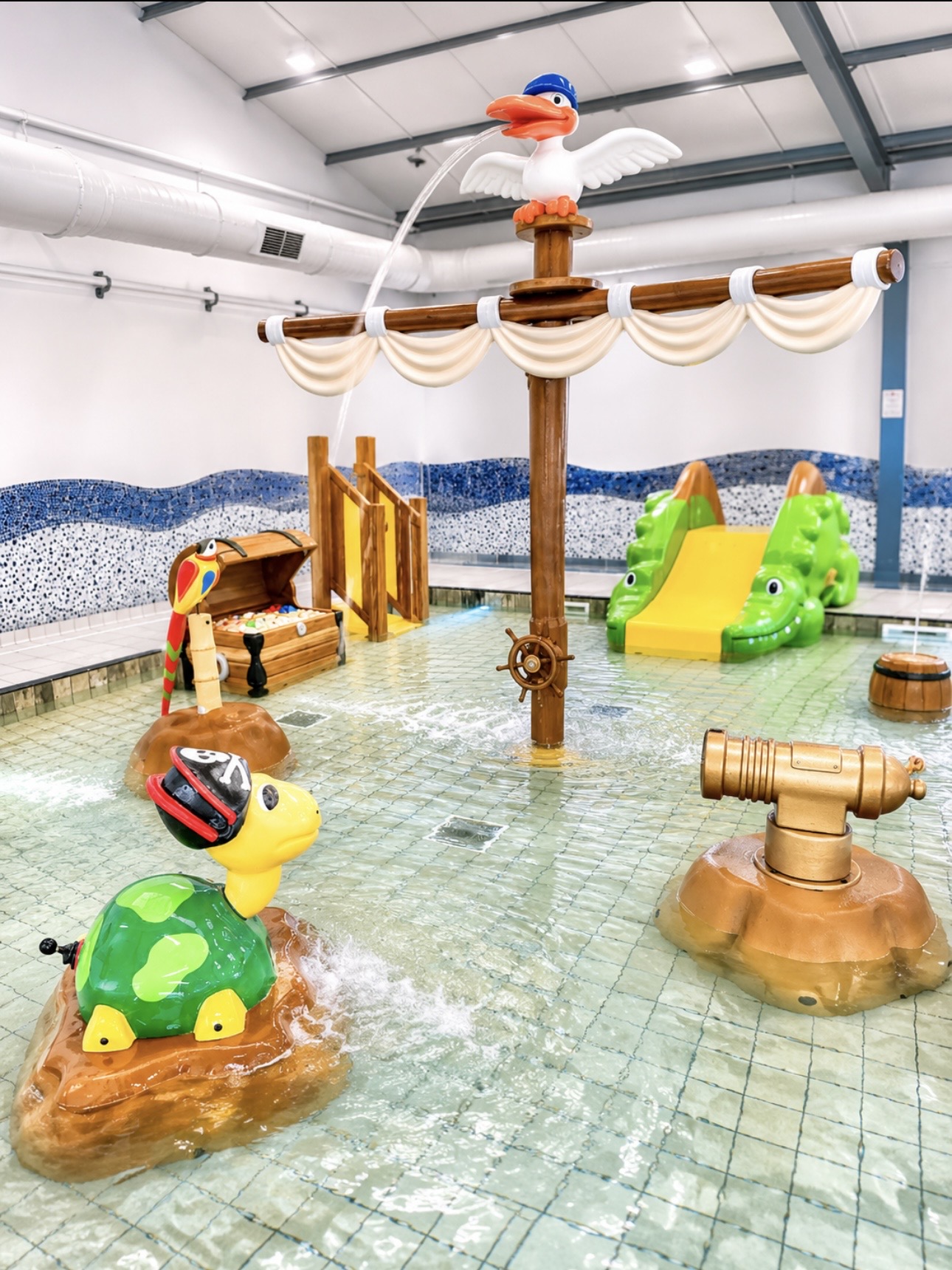 Turtle feature, water cannon and ship-themed structure in the children's splash pool